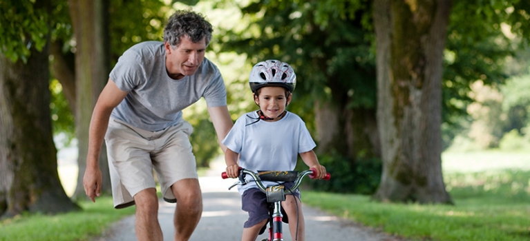 Father teaching young son to ride bicycle