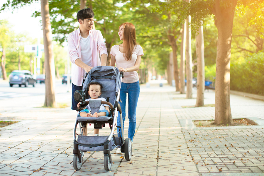 parents talking while walking baby in stroller down street